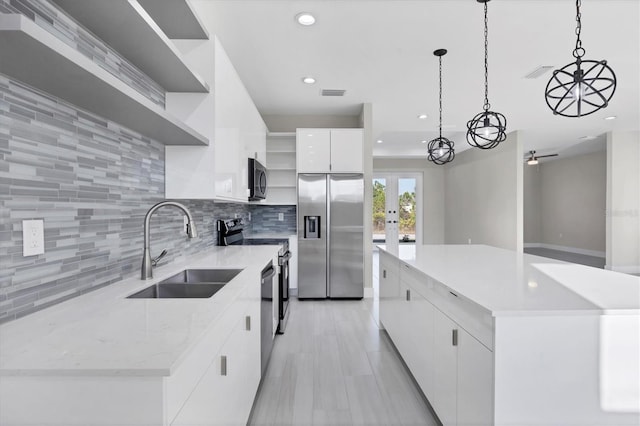 kitchen featuring stainless steel appliances, sink, pendant lighting, white cabinets, and a kitchen island