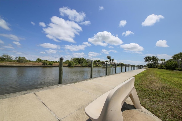 view of dock with a lawn and a water view