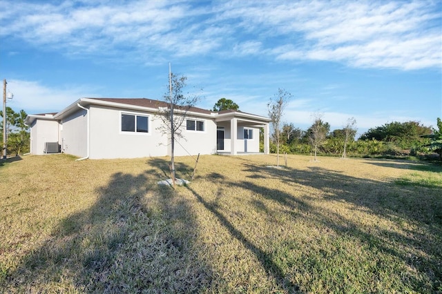 rear view of house with a lawn and central AC