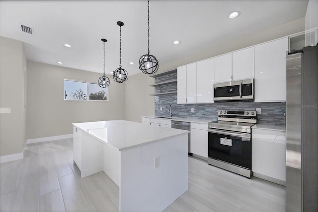 kitchen with a kitchen island, appliances with stainless steel finishes, white cabinetry, backsplash, and hanging light fixtures