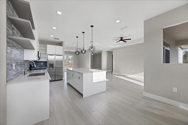 kitchen with a kitchen island, appliances with stainless steel finishes, decorative light fixtures, white cabinetry, and sink