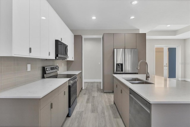 kitchen featuring appliances with stainless steel finishes, sink, a center island with sink, light hardwood / wood-style flooring, and gray cabinets