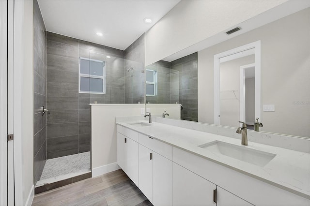 bathroom featuring hardwood / wood-style flooring, vanity, and tiled shower