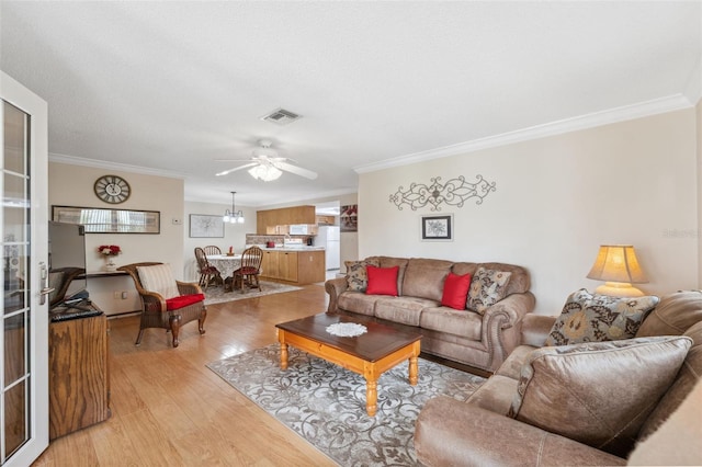 living room featuring ceiling fan with notable chandelier, light hardwood / wood-style floors, and ornamental molding