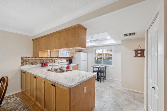 kitchen featuring kitchen peninsula, decorative backsplash, sink, and white appliances