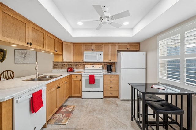 kitchen with white appliances, a raised ceiling, sink, ceiling fan, and kitchen peninsula