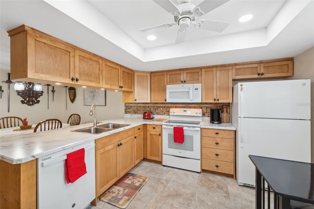 kitchen featuring kitchen peninsula, white appliances, a tray ceiling, ceiling fan, and sink