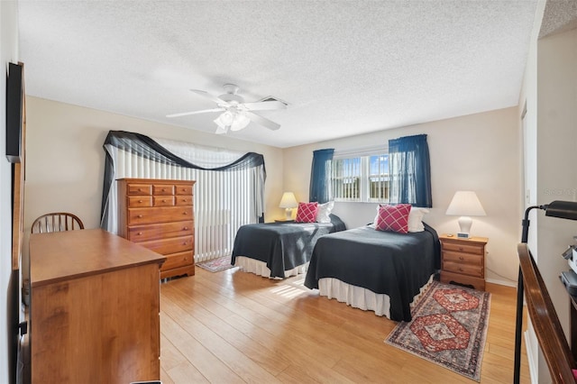 bedroom with ceiling fan, light hardwood / wood-style floors, and a textured ceiling