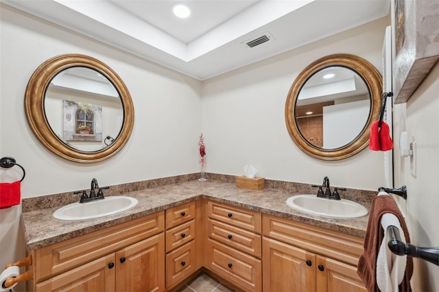 bathroom with tile patterned floors, a tray ceiling, and vanity