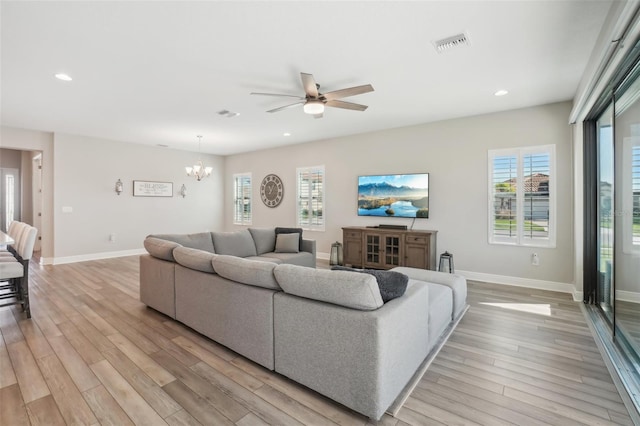 living room featuring light hardwood / wood-style flooring and ceiling fan with notable chandelier