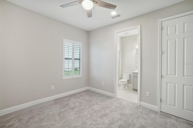 unfurnished bedroom featuring light carpet, ensuite bathroom, and ceiling fan