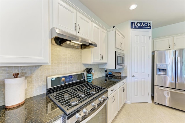 kitchen with tasteful backsplash, appliances with stainless steel finishes, white cabinets, and dark stone counters