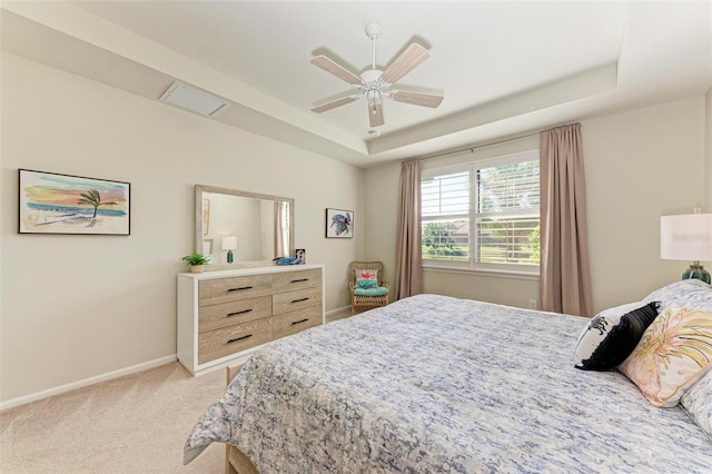 bedroom with light carpet, a raised ceiling, and ceiling fan