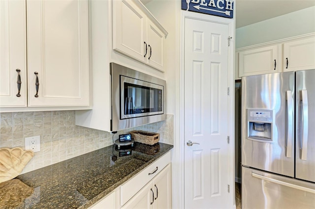 kitchen featuring tasteful backsplash, appliances with stainless steel finishes, white cabinets, and dark stone counters