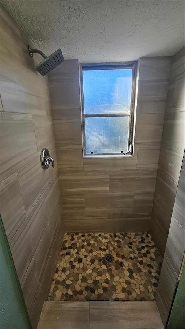 bathroom featuring a textured ceiling and tiled shower