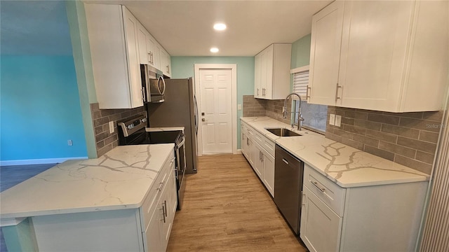 kitchen featuring sink, light hardwood / wood-style flooring, light stone counters, white cabinetry, and stainless steel appliances