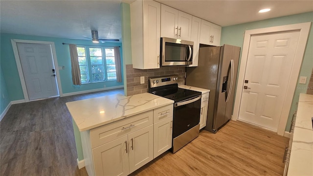 kitchen with white cabinets, light stone countertops, light wood-type flooring, and stainless steel appliances