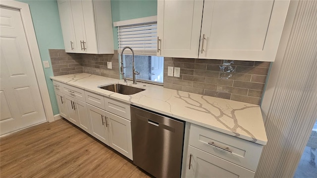 kitchen featuring white cabinetry, light stone countertops, dishwasher, sink, and light wood-type flooring