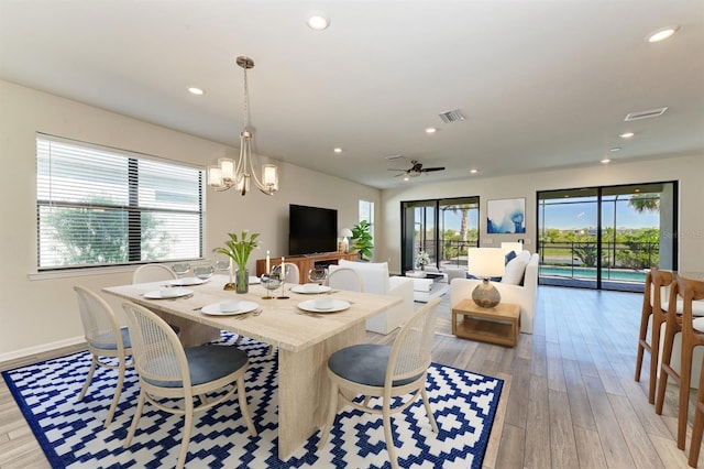 dining space with plenty of natural light, light hardwood / wood-style floors, and ceiling fan with notable chandelier