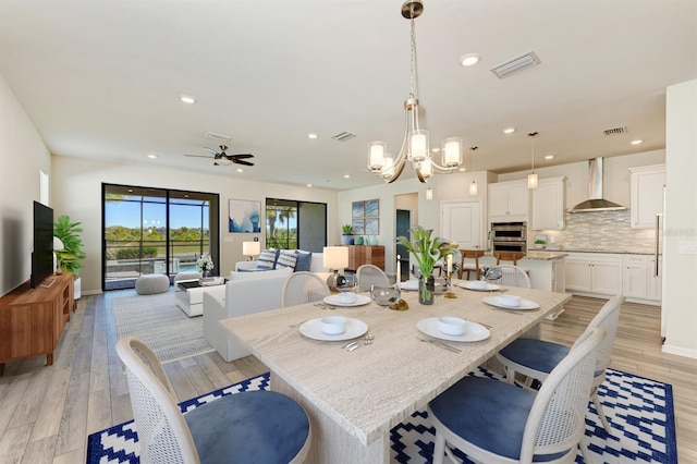 dining room featuring ceiling fan with notable chandelier and light wood-type flooring