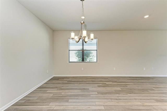 empty room featuring light wood-type flooring and a chandelier