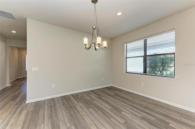 spare room featuring hardwood / wood-style flooring and a chandelier