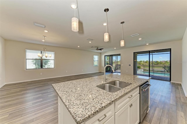 kitchen with a wealth of natural light, sink, white cabinets, and light hardwood / wood-style floors