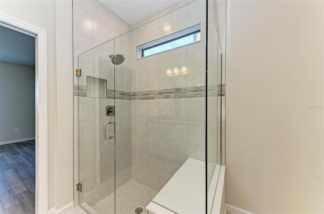 bathroom with a shower with shower door and wood-type flooring