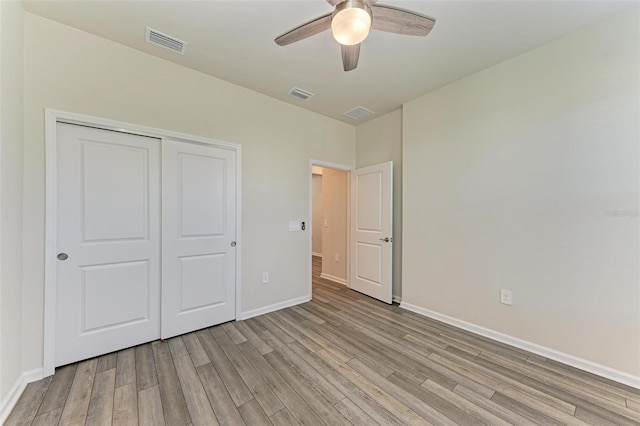 unfurnished bedroom with ceiling fan, light wood-type flooring, and a closet