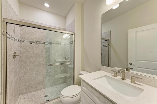 bathroom featuring a shower with door, vanity, and toilet