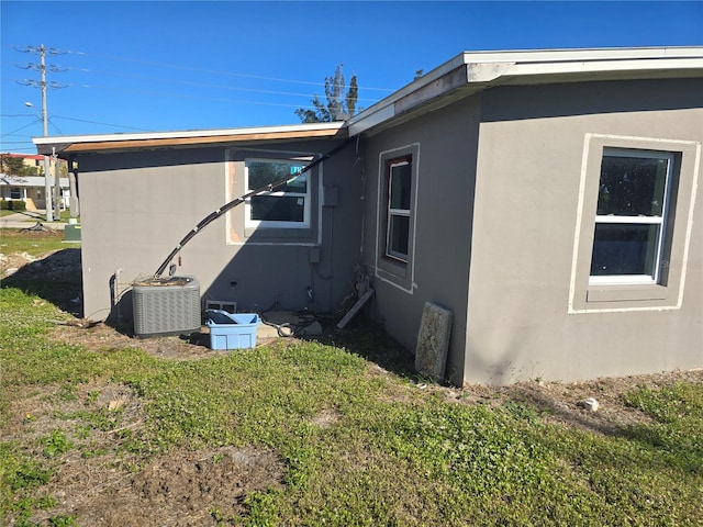 view of side of home featuring cooling unit and a yard