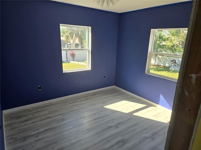 spare room featuring a notable chandelier and light hardwood / wood-style flooring