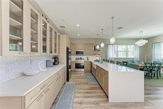 kitchen featuring light brown cabinets, hanging light fixtures, stainless steel appliances, an inviting chandelier, and tasteful backsplash