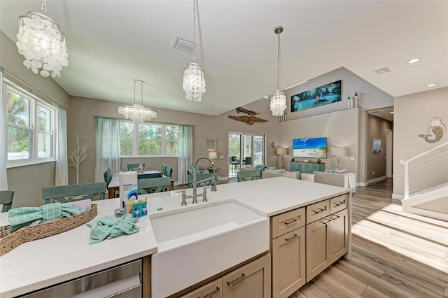 kitchen featuring an inviting chandelier, sink, light hardwood / wood-style flooring, stainless steel dishwasher, and decorative light fixtures