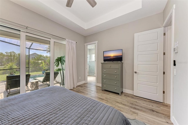 unfurnished bedroom with ceiling fan, access to exterior, light wood-type flooring, and a tray ceiling