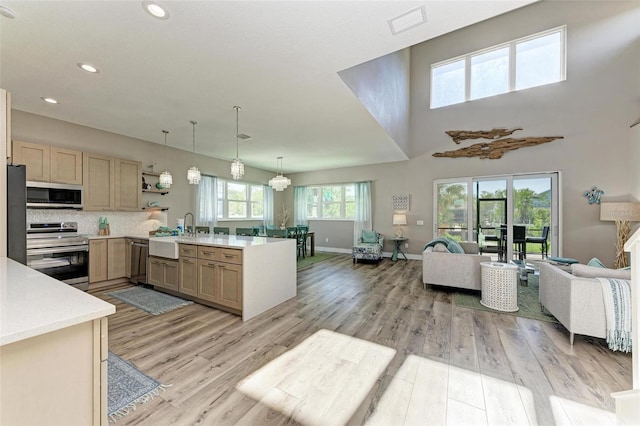 kitchen with pendant lighting, sink, light wood-type flooring, light brown cabinetry, and stainless steel appliances