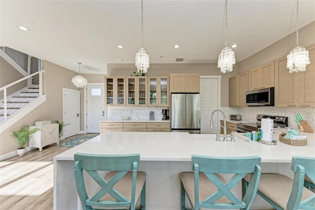 kitchen with a kitchen bar, appliances with stainless steel finishes, tasteful backsplash, and light brown cabinetry