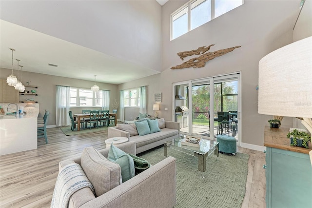 living room with light wood-type flooring, a high ceiling, and a notable chandelier