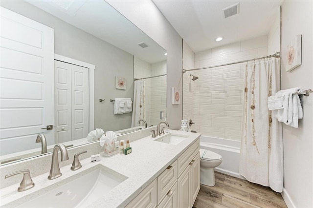 full bathroom with hardwood / wood-style floors, vanity, shower / tub combo, and toilet