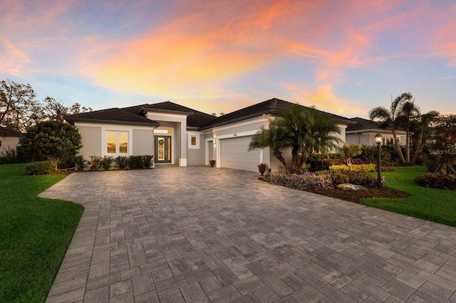 view of front of home featuring a yard, decorative driveway, an attached garage, and stucco siding