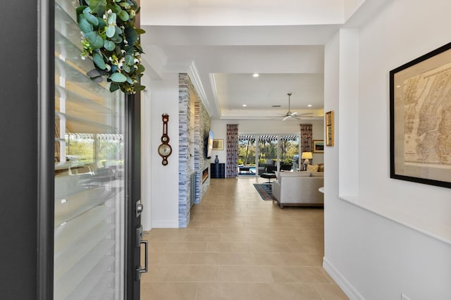 hall featuring light tile patterned floors and a raised ceiling