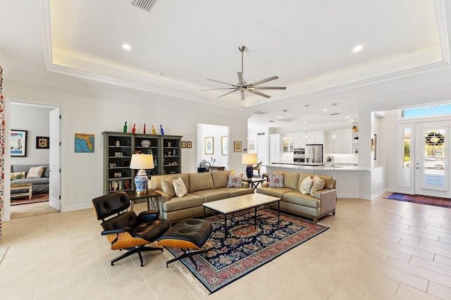 living room with a raised ceiling, ceiling fan, and crown molding