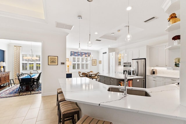 kitchen with pendant lighting, white cabinetry, sink, and a tray ceiling