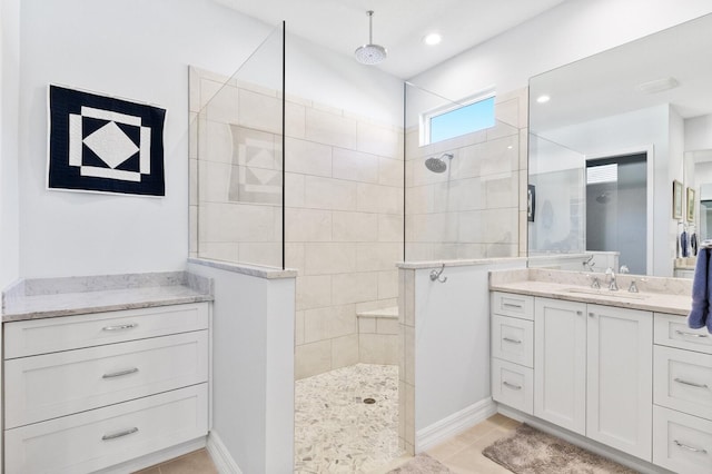 bathroom with tile patterned floors, vanity, and a tile shower