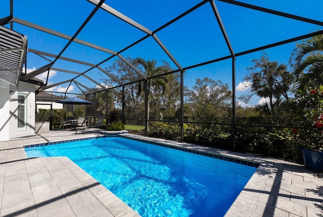 view of swimming pool featuring glass enclosure and a patio area