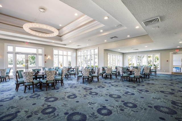 dining room featuring carpet, a textured ceiling, a raised ceiling, and ornamental molding