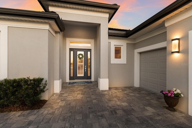 exterior entry at dusk featuring a garage