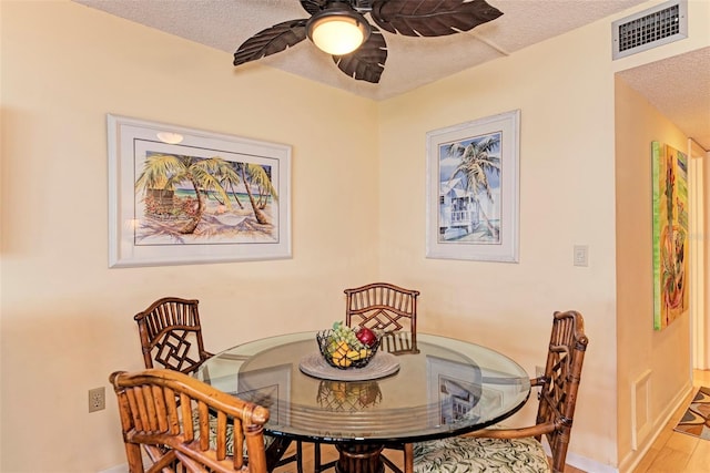 dining room featuring hardwood / wood-style floors, ceiling fan, and a textured ceiling