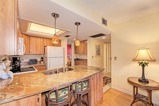 kitchen featuring sink, hanging light fixtures, kitchen peninsula, light hardwood / wood-style floors, and white appliances