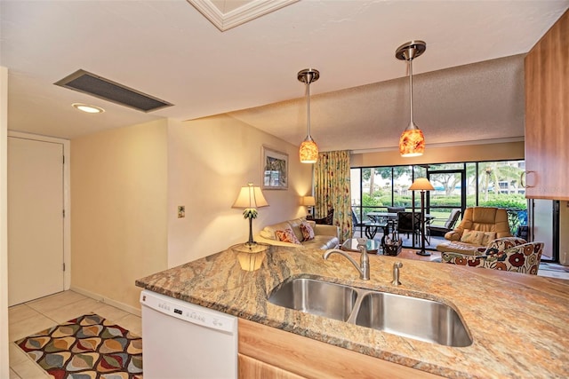 kitchen with pendant lighting, white dishwasher, light stone counters, and sink